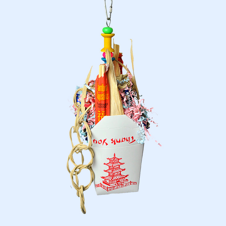 Takeout-themed parrot toy from Squawk Shop featuring a Chinese takeout box filled with colorful shredded paper, bamboo sticks, and a natural chain. Perfect for shredding, chewing, and foraging, providing enrichment for parrots and other pet birds.