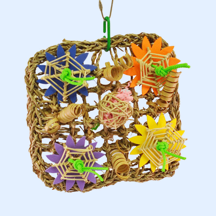 A colorful woven bird toy featuring a grid of natural seagrass, adorned with vibrant flowers and vine balls in purple, yellow, and orange. Perfect for foraging and chewing enrichment for parrots. Available at Squawk Shop.