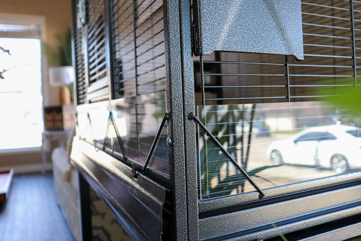 Close-up of seed catcher panels on the Elegant Flight Cage, showing durable black metal build and protective side guards — Squawk Shop feature detail