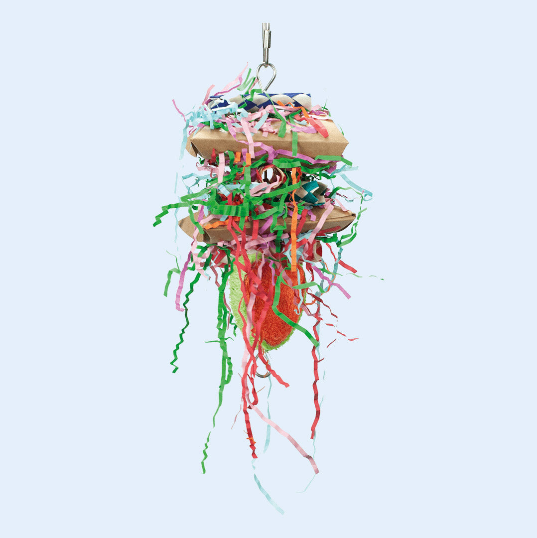 A colorful hanging bird toy featuring layers of crinkle paper, cardboard, and loofah, designed for shredding, chewing, and foraging. Provides mental stimulation and enrichment for parrots. Available at Squawk Shop.