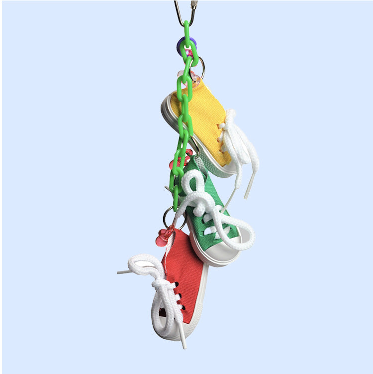 A fun bird toy from Squawk Shop featuring miniature sneakers hanging from a plastic chain, designed for preening, tugging, and interactive play.