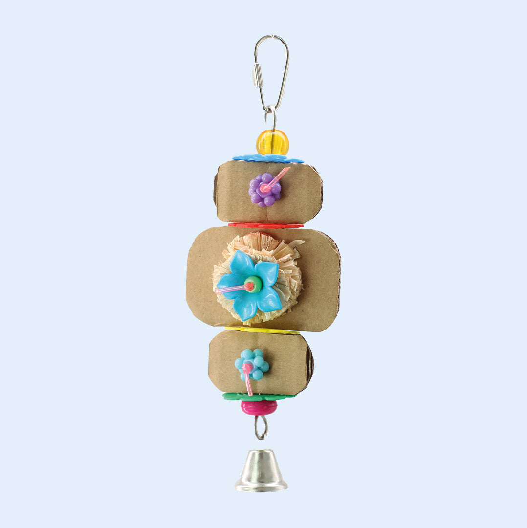 Surf’s Up Bird Toy with cardboard layers, floral accents, beads, and a bell, available at Squawk Shop for playful birds.