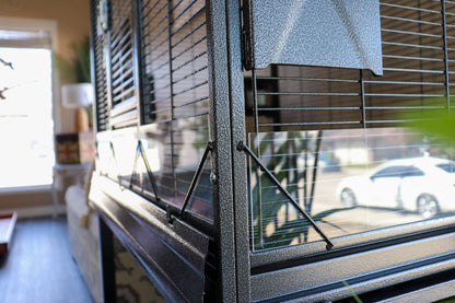 Close-up of seed catcher panels on the Elegant Flight Cage, showing durable black metal build and protective side guards — Squawk Shop feature detail