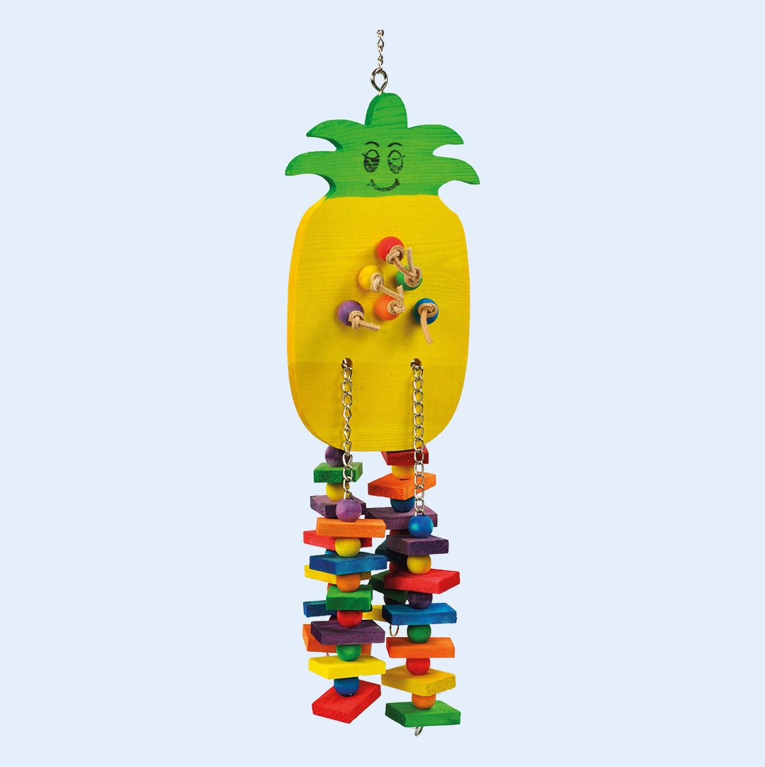 A colorful parrot toy in the shape of a pineapple, featuring a yellow wooden base with green leaves at the top and a cheerful face design. The toy has colorful wooden blocks, beads, and chains hanging below for parrot enrichment and play. Available at Squawk Shop